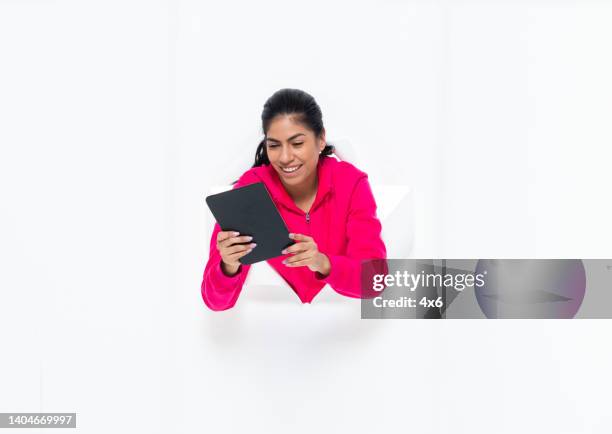 generation z female in front of white background wearing jeans and using digital tablet - fab fragment stock pictures, royalty-free photos & images