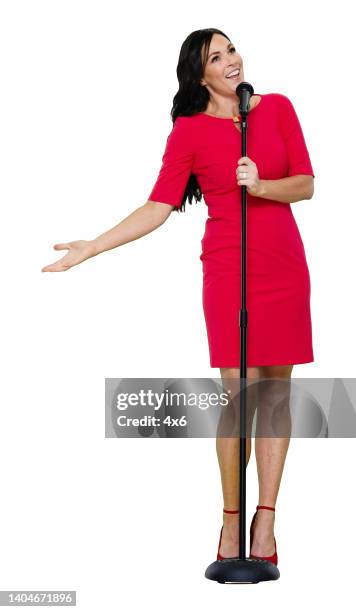 caucasian female singer dancing in front of white background wearing dress and holding microphone stand - singer isolated stock pictures, royalty-free photos & images