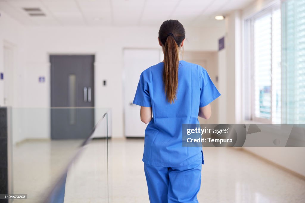 Un'infermiera cammina lungo il corridoio in un ospedale.