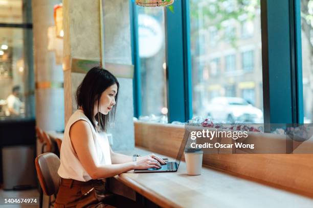 young asian woman working with laptop in coworking space - サテン ストックフォトと画像