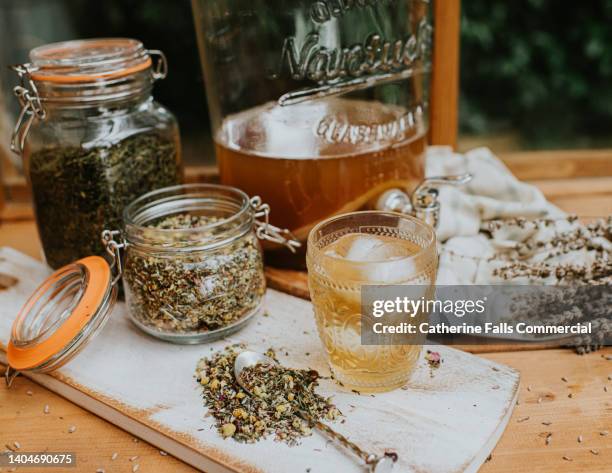 various dried ingredients in mason jars on a wooden chopping board beside a probiotic drink with ice - ice tea stockfoto's en -beelden