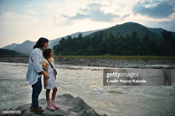 mother and daughter standing on the rocks at the bank of a river - northeast india stock pictures, royalty-free photos & images