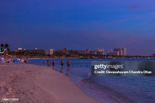 it is just after sunset in the tourist resort of palm beach in aruba on the south caribbean sea. several beach hotels and boats at anchor offshore can be seen - palm beach aruba stockfoto's en -beelden