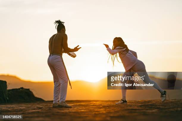 paar übt capoeira bei sonnenuntergang - folkloric stock-fotos und bilder
