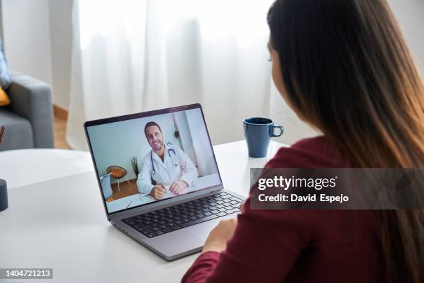 over-the-shoulder view of a girl sitting at the salon table consulting with her therapist online. - telemedicine stock pictures, royalty-free photos & images