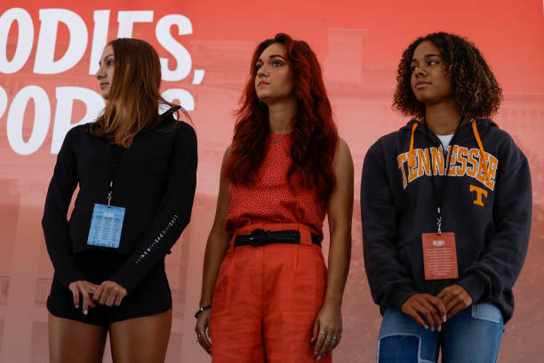 Chelsea Mitchell, Selina Soule and Alanna Smith, three former Connecticut high school track athletes, listen during an "Our Bodies, Our Sports" rally...