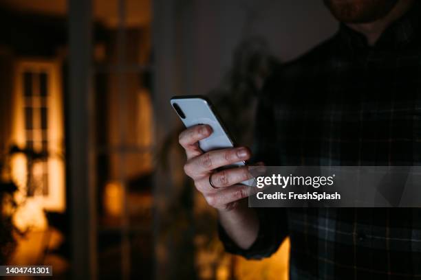 an unrecognizable businessman texting on his mobile phone while working his night shift from home - smartphone dark stock pictures, royalty-free photos & images