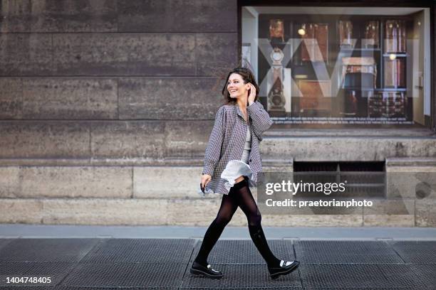 portrait of woman walking on the street and wind blowing her skirt - paris fashion stock pictures, royalty-free photos & images