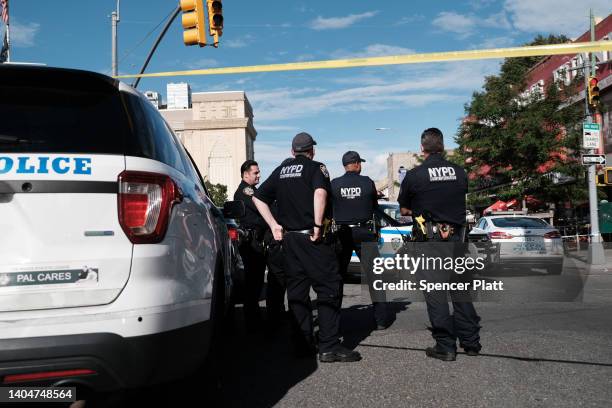 Police gather at the scene of a shooting where an officer was shot in his patrol car in Brooklyn on June 23, 2022 in New York City. The shooting...