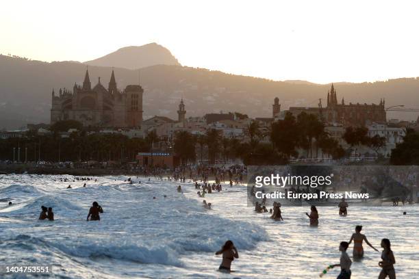 Hundreds of people bathe on the beach in front of the previous celebration of the 'correfoc', on 23 June, 2022 in Palma de Mallorca, Balearic...