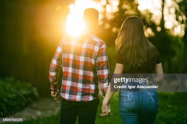 young couple holding hands at sunset - bright future stock pictures, royalty-free photos & images