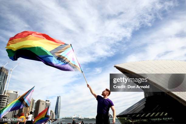 Man wields a rainbow flag as 1,000 people form a human progress flag on the steps of the Opera House to mark the 44th anniversary or the Sydney Gay...