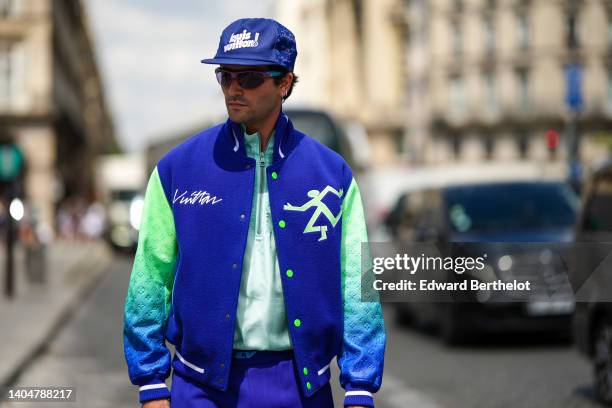 Marc Forne wears royal blue with embroidered white pattern cap from Louis Vuitton, purple sunglasses, silver earrings, a pale green t-shirt, a royal...