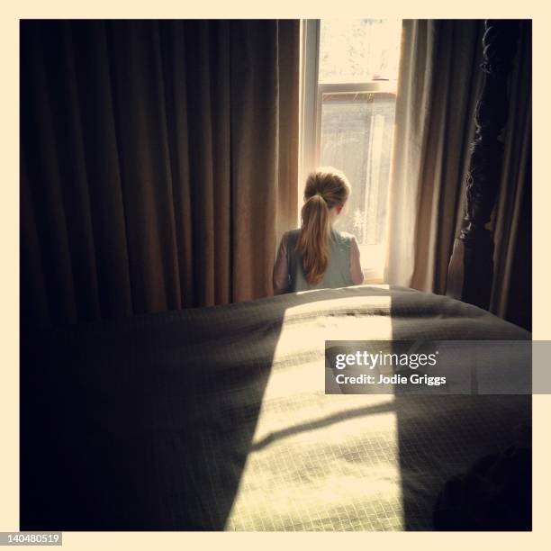 girl looking out window - bedroom curtains stock pictures, royalty-free photos & images