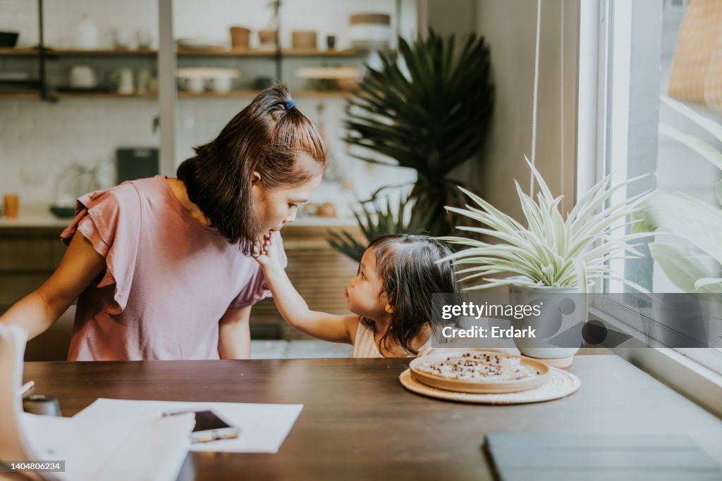 Cute girl sharing her mom some delicious homemade chocolate chip cookies.