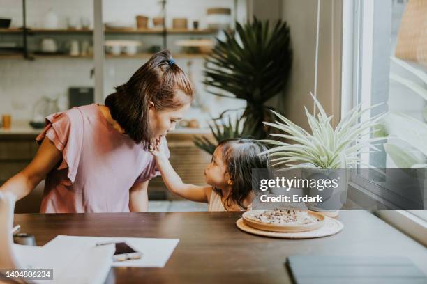 cute girl sharing her mom some delicious homemade chocolate chip cookies. - finger bun stock pictures, royalty-free photos & images