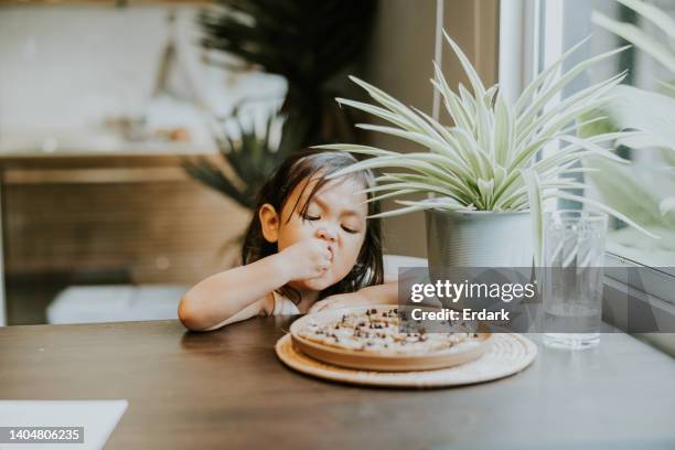 thai toddler girl enjoy eating with homemade cookies from her mom. - licking finger stock pictures, royalty-free photos & images