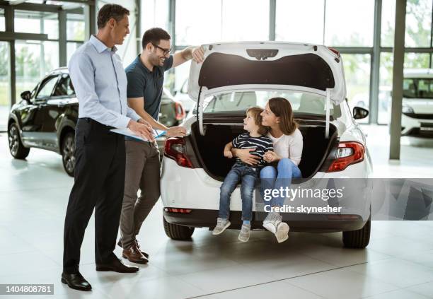 happy family buying a car in a showroom. - buying a car stock pictures, royalty-free photos & images