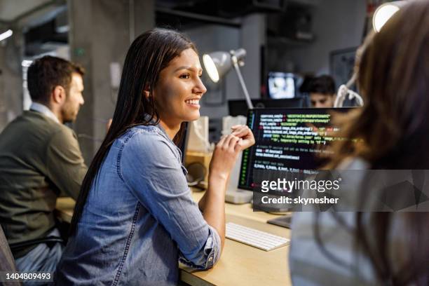 happy female programmer talking to her colleague in the office. - happy programmer stock pictures, royalty-free photos & images