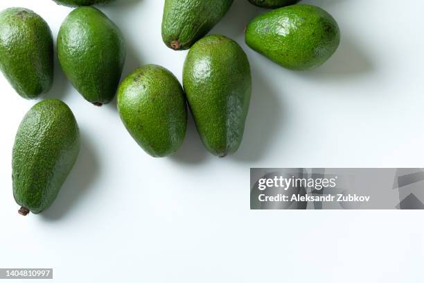 green ripe avocados on a white table or background. vegetarian, vegan and raw food. the concept of vegetarianism, veganism, and raw food. healthy fats. copy space. - fruktkött bildbanksfoton och bilder