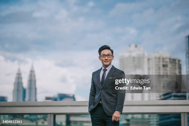 portrait asian chinese successful businessman looking at camera smiling with cityscape background - chinese people posing for camera stockfoto's en -beelden