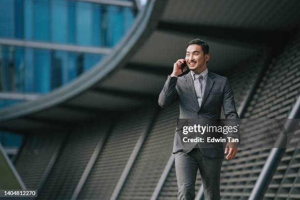 successful asian chinese businessman talking through smart phone outside of financial building - chinese male confident stock pictures, royalty-free photos & images