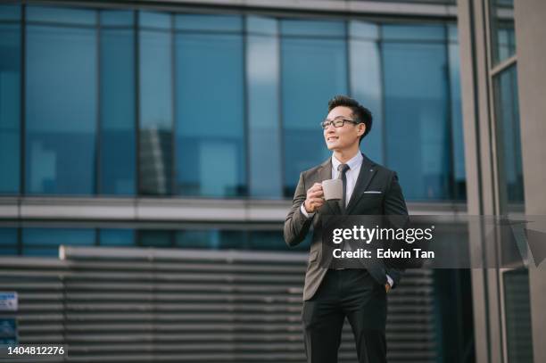 portrait successful asian chinese businessman holding coffee cup looking away outside office building - see the bigger picture stock pictures, royalty-free photos & images