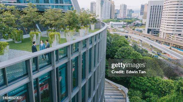 drone point of view business person talking on roof top garden outside office building - kantoorgebouw stockfoto's en -beelden