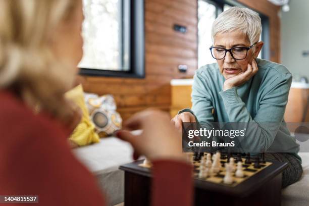 relaxed mature women playing chess at home. - senior playing chess stock pictures, royalty-free photos & images