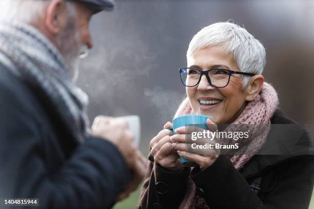 happy senior couple drinking hot drink in nature. - mature couple winter outdoors stockfoto's en -beelden