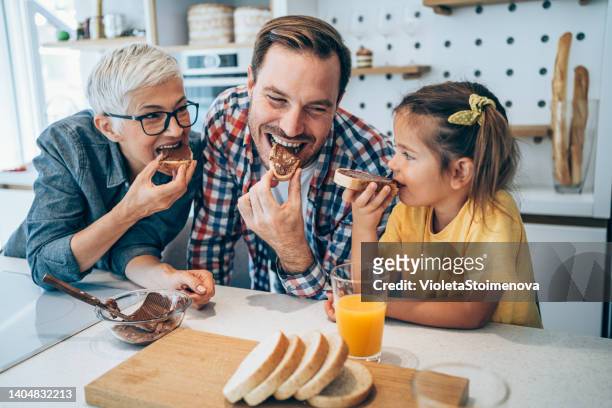 glückliche familie frühstücken. - biting into chocolate stock-fotos und bilder