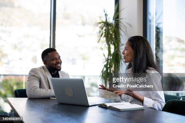 mixed race woman giving presentation to senior colleague in boardroom - wealth management stock pictures, royalty-free photos & images