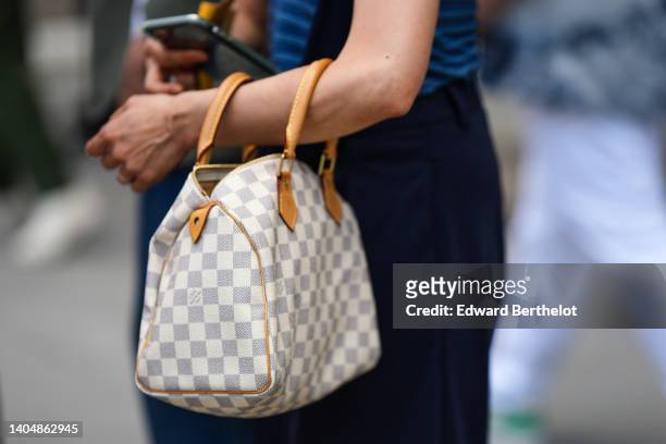 Guest wears a white and gray checkered print pattern in coated canvas Speedy handbag from Louis Vuitton, outside the Louis Vuitton show, during Paris...