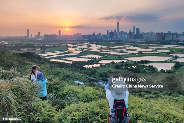 Hikers take photos of buildings in Shenzhen beyond farmland in the Lok Ma Chau area on October 5, 2021 in Hong Kong, China.