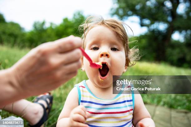 baby girl eating meal - onschuld stockfoto's en -beelden