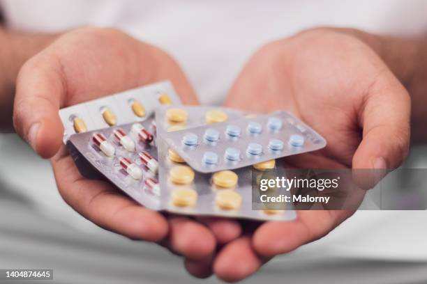 young man holding multiple pill blisters in his hands. - 止痛劑 個照片及圖片檔