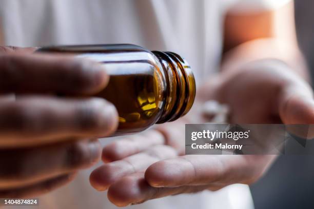 young man spilling multiple pills in his hand. - kapsel stock-fotos und bilder