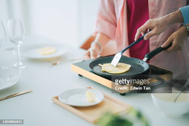 週末の余暇に妻と一緒にキッチンカウンターでパンケーキを調理するアジア系中国人シニア男性 - electric stove burner ストックフォトと画像