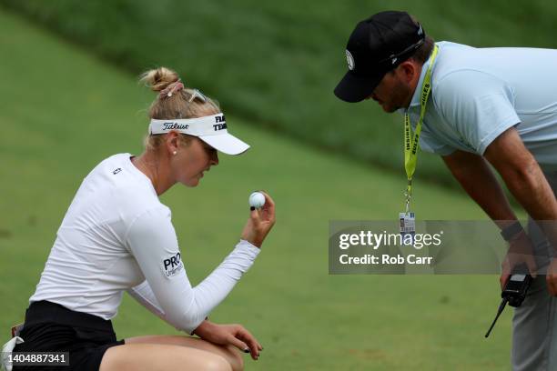 Jessica Korda of the United States and a rules official inspect Korda's golf ball after it bounced off a cart path and landed on the 12th fairway...