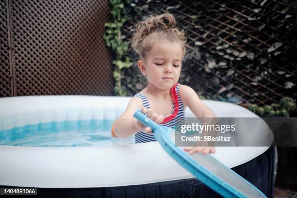 girl cleaning pool with net - plastic pool stock-fotos und bilder