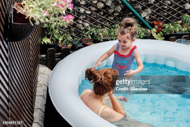 mother and daughter having fun in a garden pool - girls in hot tub stockfoto's en -beelden