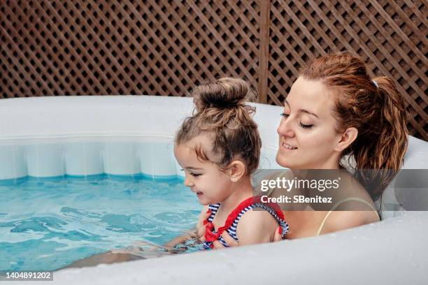 mother and daughter in an inflatable hot tub - girls in hot tub stockfoto's en -beelden