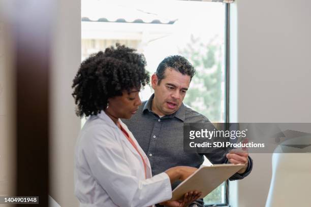 male patient and female doctor gesture while discussing treatment plan - 50 year old male patient stock pictures, royalty-free photos & images