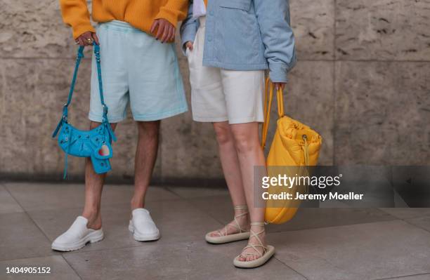Nelson Tiberghien seen wearing an orange knit turtleneck pullover, a light blue shorts, a blue leather Balenciaga Cagole bag, white nylon sneakers;...