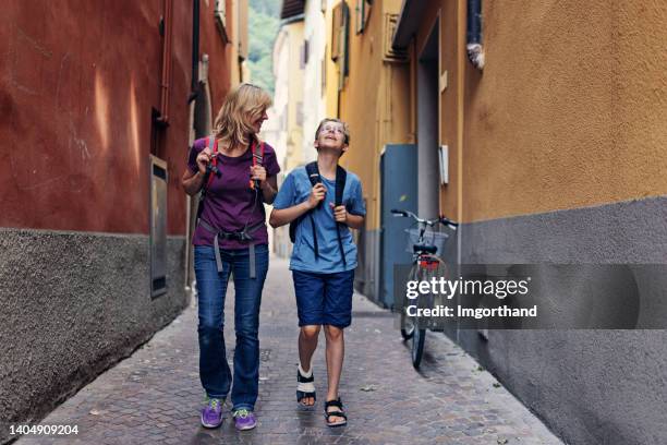 mãe e filho caminhando na rua estreita de riva del garda - riva del lago - fotografias e filmes do acervo