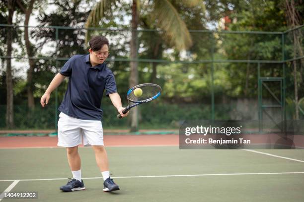 asian chinese down syndrome male tennis player practicing in tennis court during weekend morning - bouncing stock pictures, royalty-free photos & images