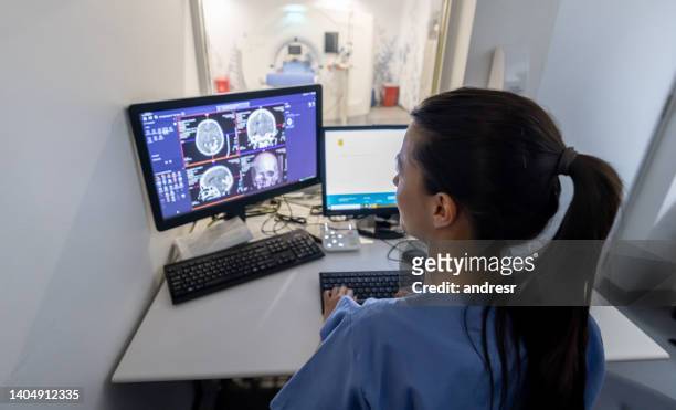 radiologist in the control room performing an mri scan - tomografia por emissão de positrões imagens e fotografias de stock