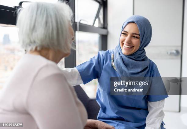 infermiera musulmana che parla con un paziente anziano in ospedale - hijab foto e immagini stock