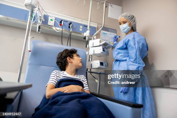 oncology nurse talking to a young patient getting his treatment - iv infusion stock pictures, royalty-free photos & images