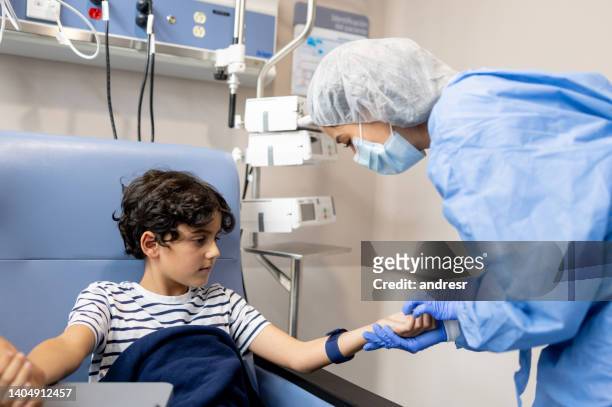 menino em quimioterapia olhando para uma enfermeira encontrando uma veia em seu braço - infused - fotografias e filmes do acervo